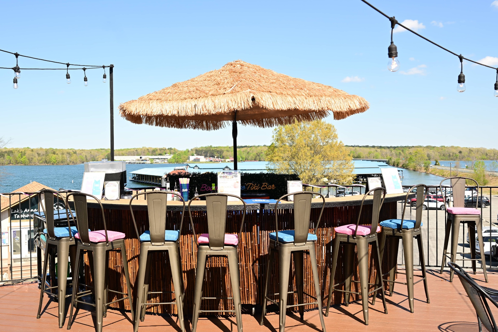 Bougie Breeze tiki bar at Lake Anna with a thatched umbrella, bamboo bar, metal stools, and lake view